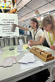 Zwei Besucherinnen beim Stempeln des Fingeralphabets
