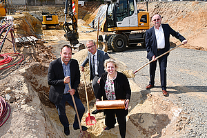 Gruppenfoto der Beteiligten beim Legen des Grundsteins in der Baugrube