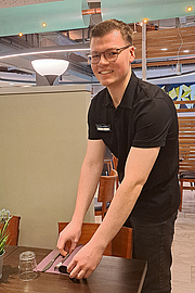 Tom Wahle arbeitet im Service. Tom Wahle beim Eindecken eines Tisches