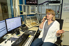 Eine Frau mit Telefonhörer in der Hand nimmt gerade einen Anruf entgegen