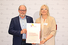 Der Personalleiter und die Frauenbeauftragte halten gemeinsam das große Zertifikat in den Händen.