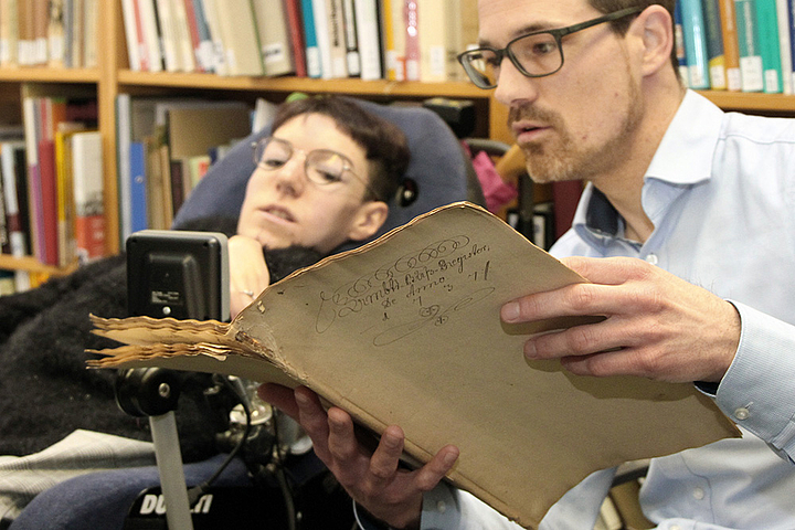 Zwei Personen bei der Sichtung eines historischen Dokuments