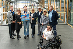(v.l.): Kathrin Kappes-Kühnemuth (Leiterin Überregionale Schulen beim LWV), Danica Waitkus (Lufthansa Initiative Sunflower), Gewinnerin Hannah Stenzinger, Lufthansa-Schwerbehindertenvertrauensperson (SBV) Ste Gruppenfoto von der Preisverleihung mit Hannah Stenzinger in der Mitte, die ihr Siegerbild hochhält.