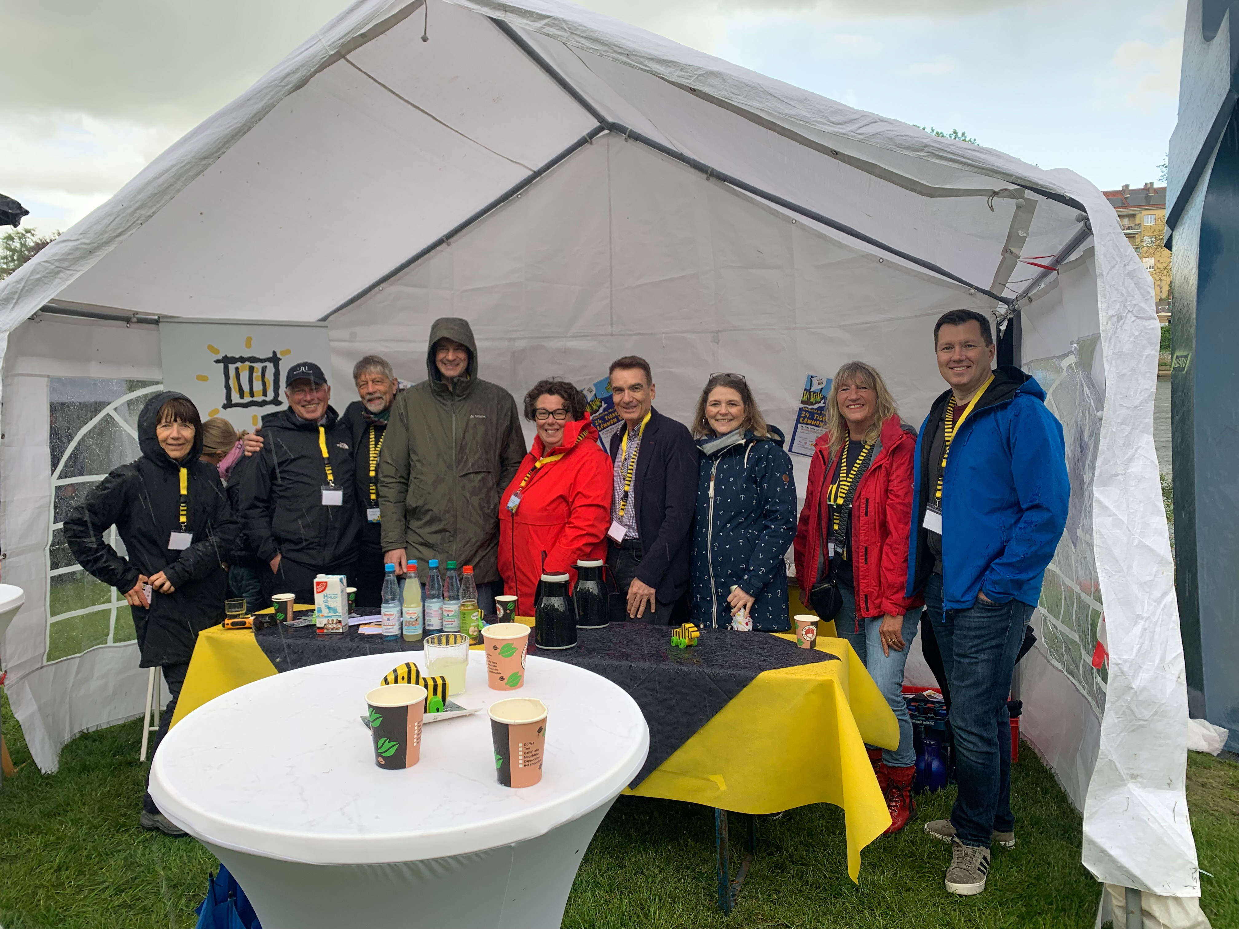 Helferinnen und Helfer stehen hinter einem Stand des Tigerentenrennens.